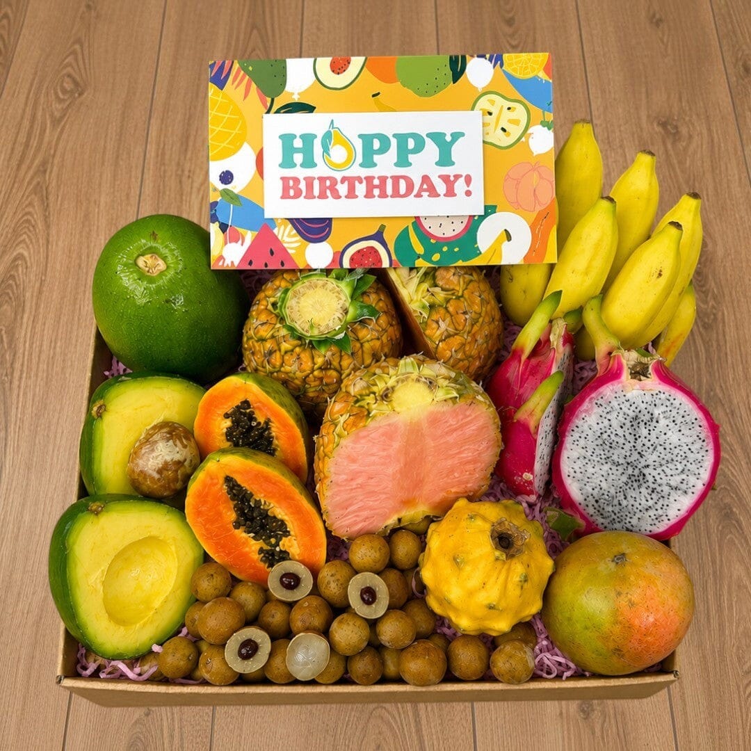 Tropical Fruit Box gift set featuring pink pineapple, dragon fruit, mango, avocado, and bananas with birthday card.