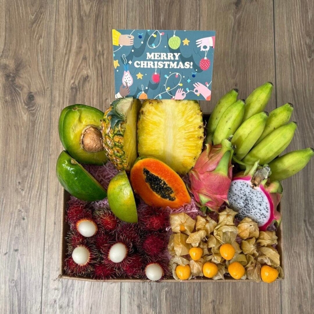 Tropical Fruit Box gift set featuring mango, pineapple, avocado, dragon fruit, bananas, and rambutan with a card.