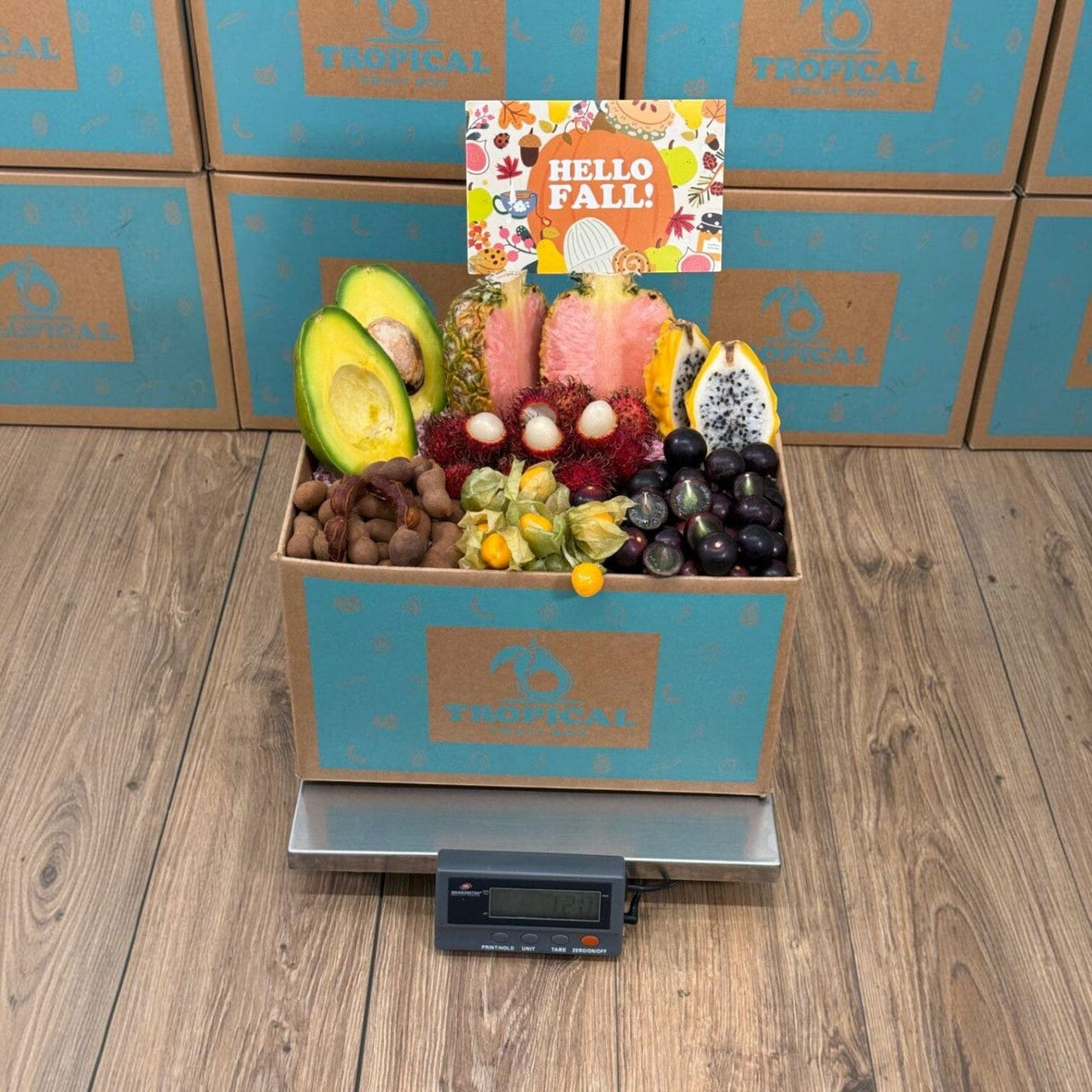 Tropical Fruit Box Fall Fruit Feast featuring pink pineapple, avocado, dragon fruit, and golden berries in a gift box.