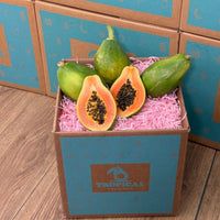 Thumbnail for Tropical Fruit Box Golden Papaya, one cut in half showing vibrant orange flesh and black seeds, surrounded by whole green papayas.