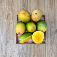 Thumbnail for Tropical Fruit Box Kent mangoes with greenish-yellow skin and one sliced open to reveal juicy orange flesh in a box