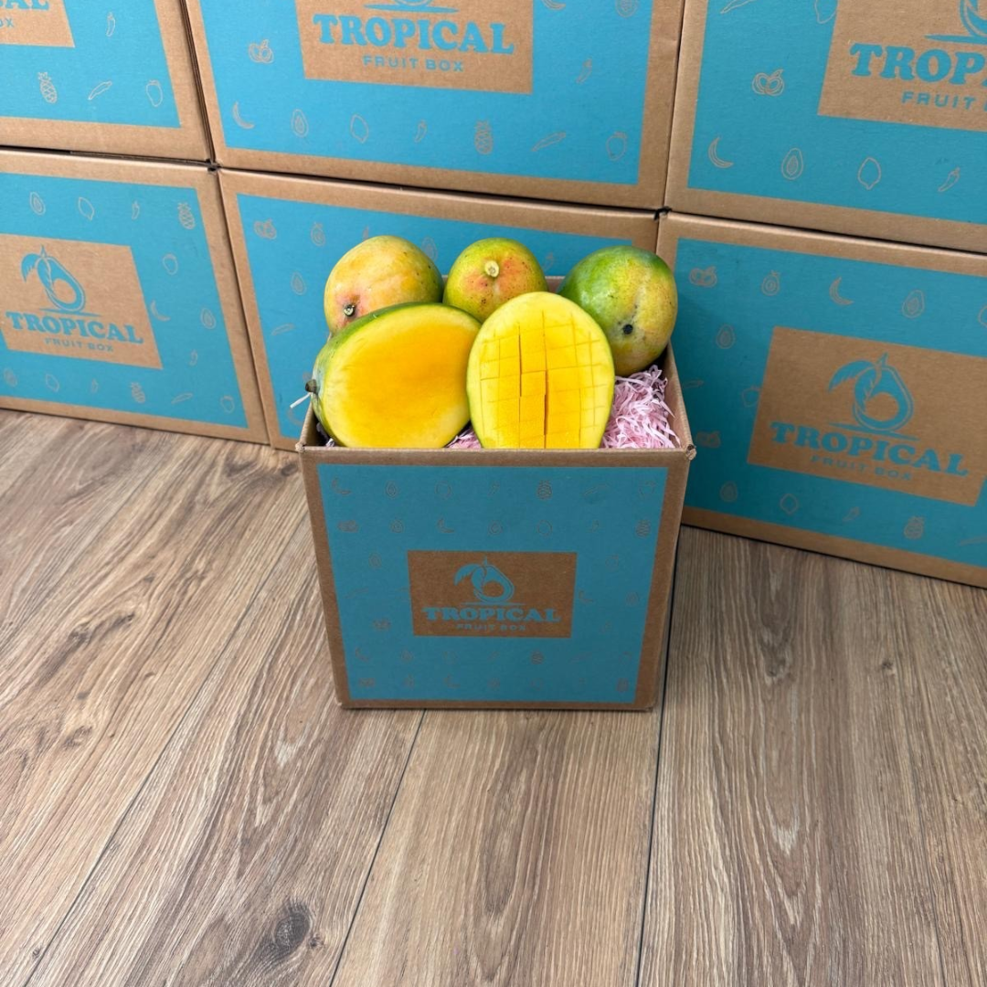 Tropical Fruit Box Kent mangoes with smooth greenish-yellow skin and juicy orange flesh in a branded shipping box.