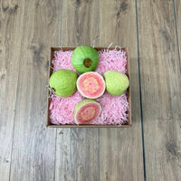 Thumbnail for Tropical Fruit Box Pink Guava, 3 lbs. Fresh pink guavas, one cut in half revealing rosy flesh, arranged in a box with pink shred.