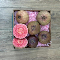 Thumbnail for Tropical Fruit Box Purple Guava, whole and halved, revealing vibrant pink flesh and seeds. Six fruits in a box with pink shred.