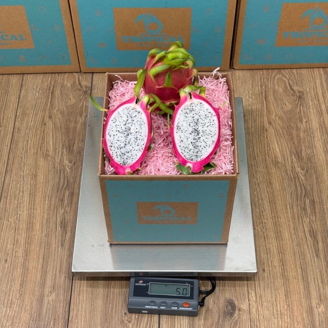 Tropical Fruit Box red dragon fruit, white flesh with black seeds, on pink shredded paper in a teal box.