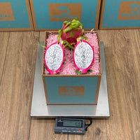 Thumbnail for Tropical Fruit Box red dragon fruit, white flesh with black seeds, on pink shredded paper in a teal box.