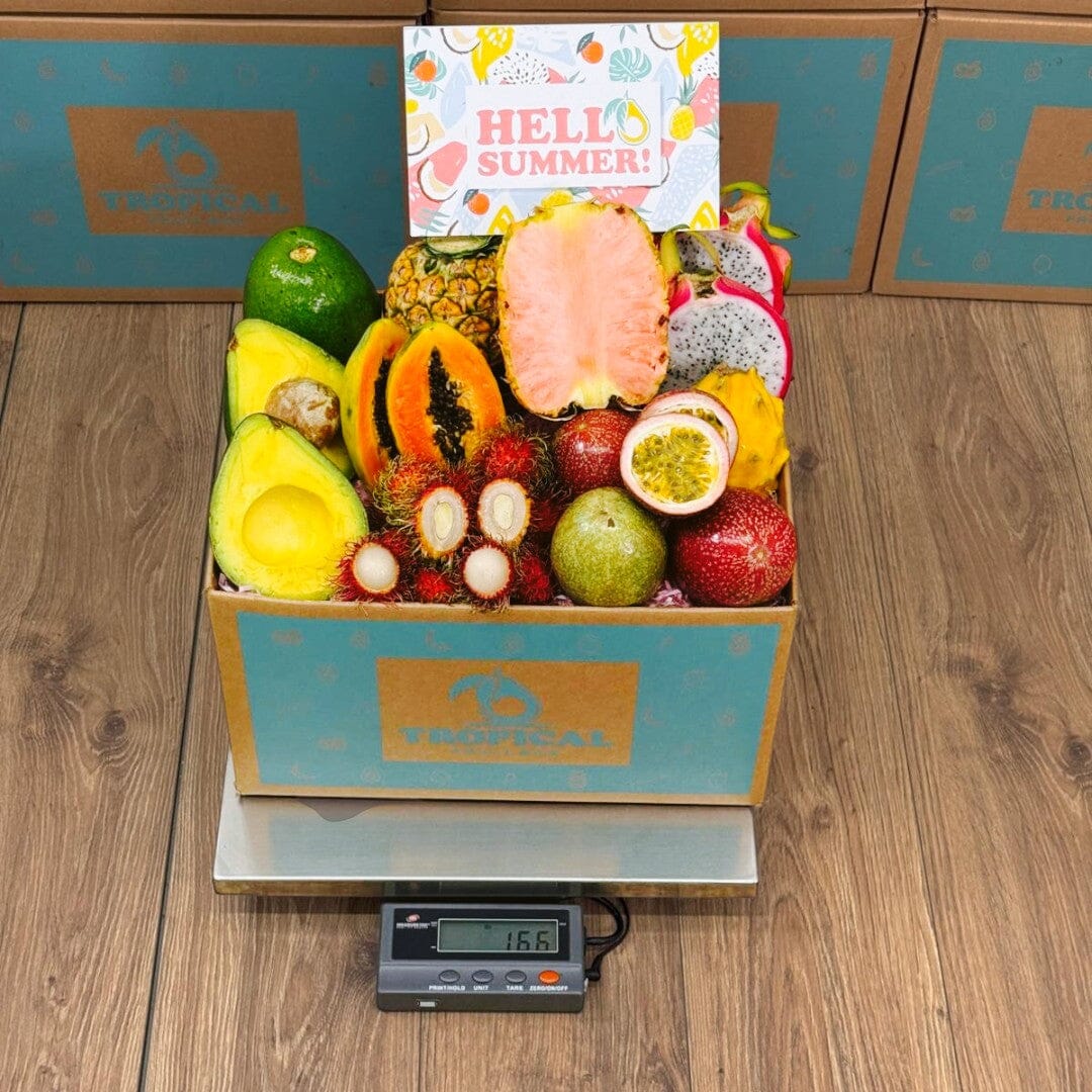 Tropical Fruit Box filled with fresh pink pineapple, dragon fruit, passion fruit, papaya, and avocado for summer.